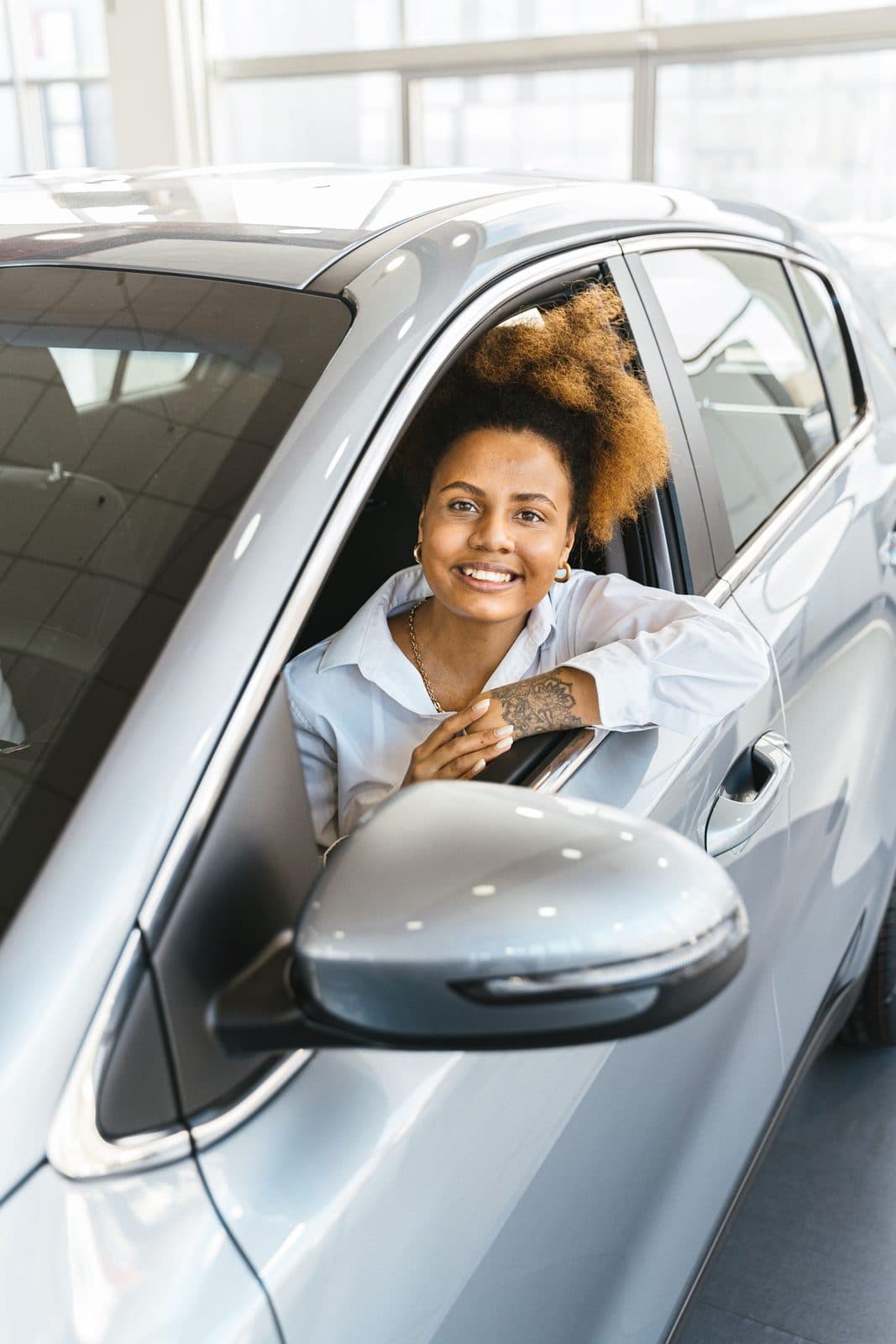 Cliente souriante au volant d'un véhicule neuf en concession